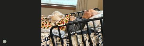 A photo of Gary's dad lying in his hospital bed with his dog on his lap.